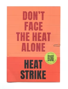 A bright orange pamphlet with bold text reading "don't face the heat alone" at the top and "heat strike" at the bottom, with a small logo and text on the right indicating an event or campaign related to heat safety or climate action. a paperclip is attached to the top left corner of the pamphlet.