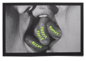 Artistic black and white photo featuring a close-up of a mouth slightly open, with colored candy tablets resting on the tongue, each inscribed with a different word, in a critique or commentary on topics or personalities.