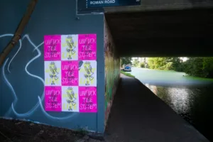 Colorful urban art on display under a bridge along a peaceful waterway, where street art contrasts with the tranquility of nature.