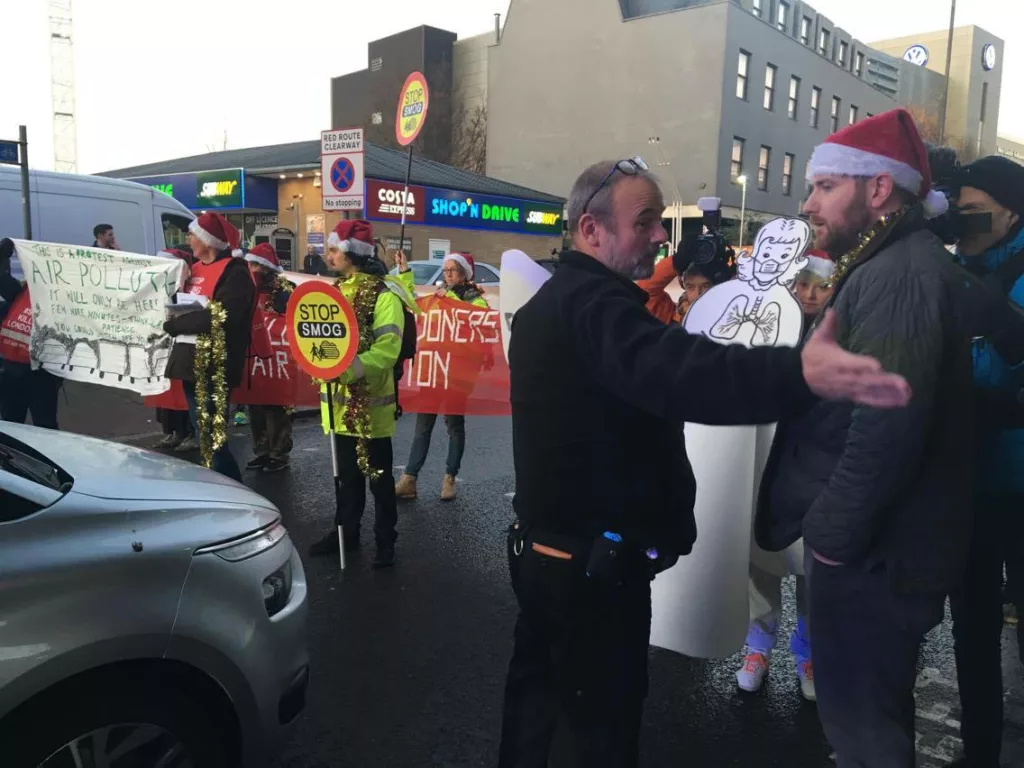 A group of protesters dressed in christmas atire and as a lollypop lady stop traffic in protest of air pollution in London.