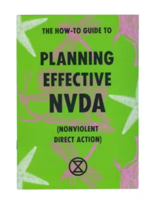 A book cover titled "the how-to guide to planning effective nvda (nonviolent direct action)" with a bright green background, adorned with illustrations of foliages and insects in pink and white, featuring bold typography and an emblem of a circled a, often associated with anarchy, at the bottom center.