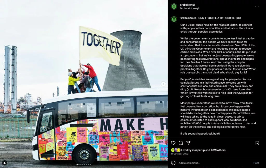 A colorful bus covered in environmental slogans and imagery, promoting climate action and unity, stands out against an industrial backdrop.