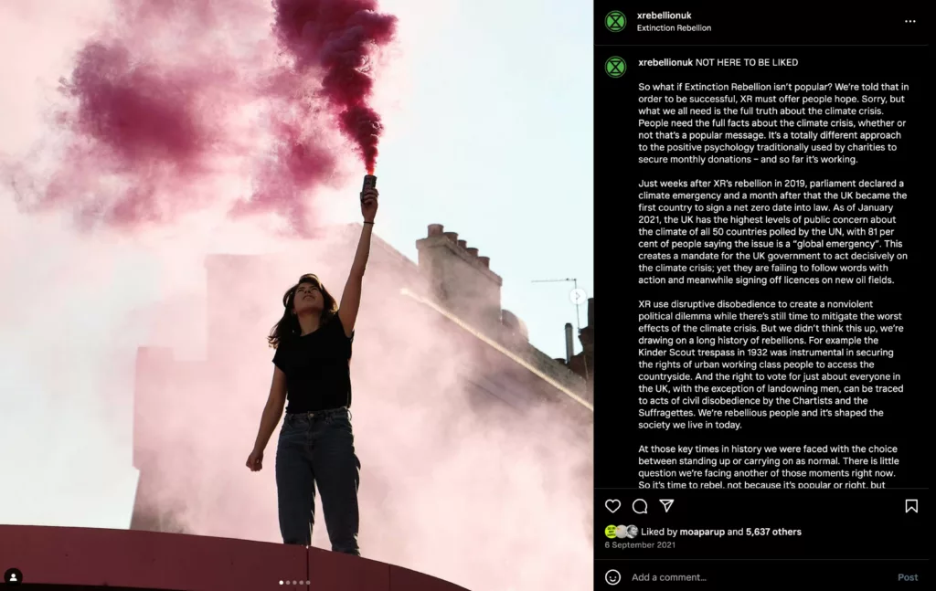 A person standing with arms outstretched, facing a vibrant pink smoke flare with a clear blue sky in the background, evoking a sense of empowerment and freedom.